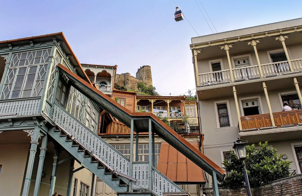 Rzeźbione balkony starego miasta, w tle kolejka linowa, Tbilisi
